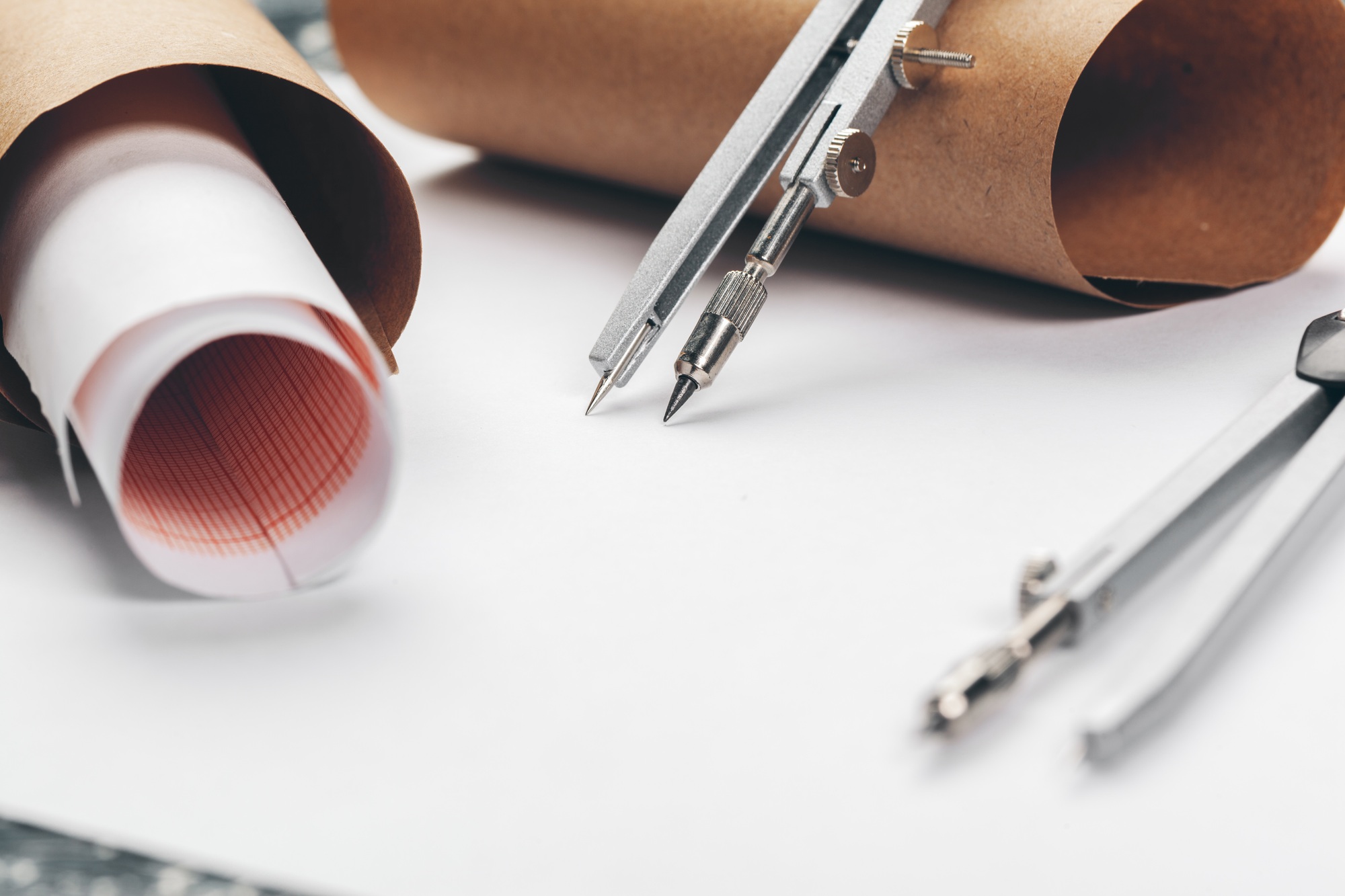 Architectural blueprints and blueprint rolls and a drawing instruments on the worktable